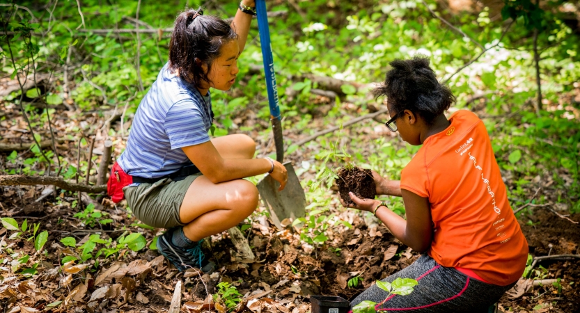 two young people use gardening tools during a service day with outward bound